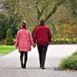 Persona che cammina in un parco, monitorando i passi con un dispositivo.